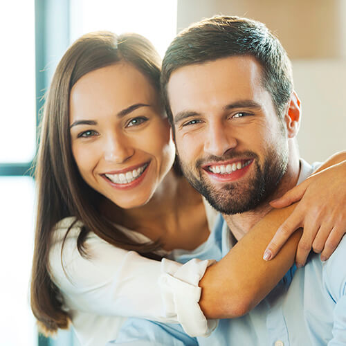 A young couple with dental crowns smiling together