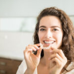 Woman holding an Invisalign® aligner to straighten her teeth